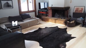 Una sala de estar con un sofá, una mesa de centro, una chimenea y un tapete negro grande.