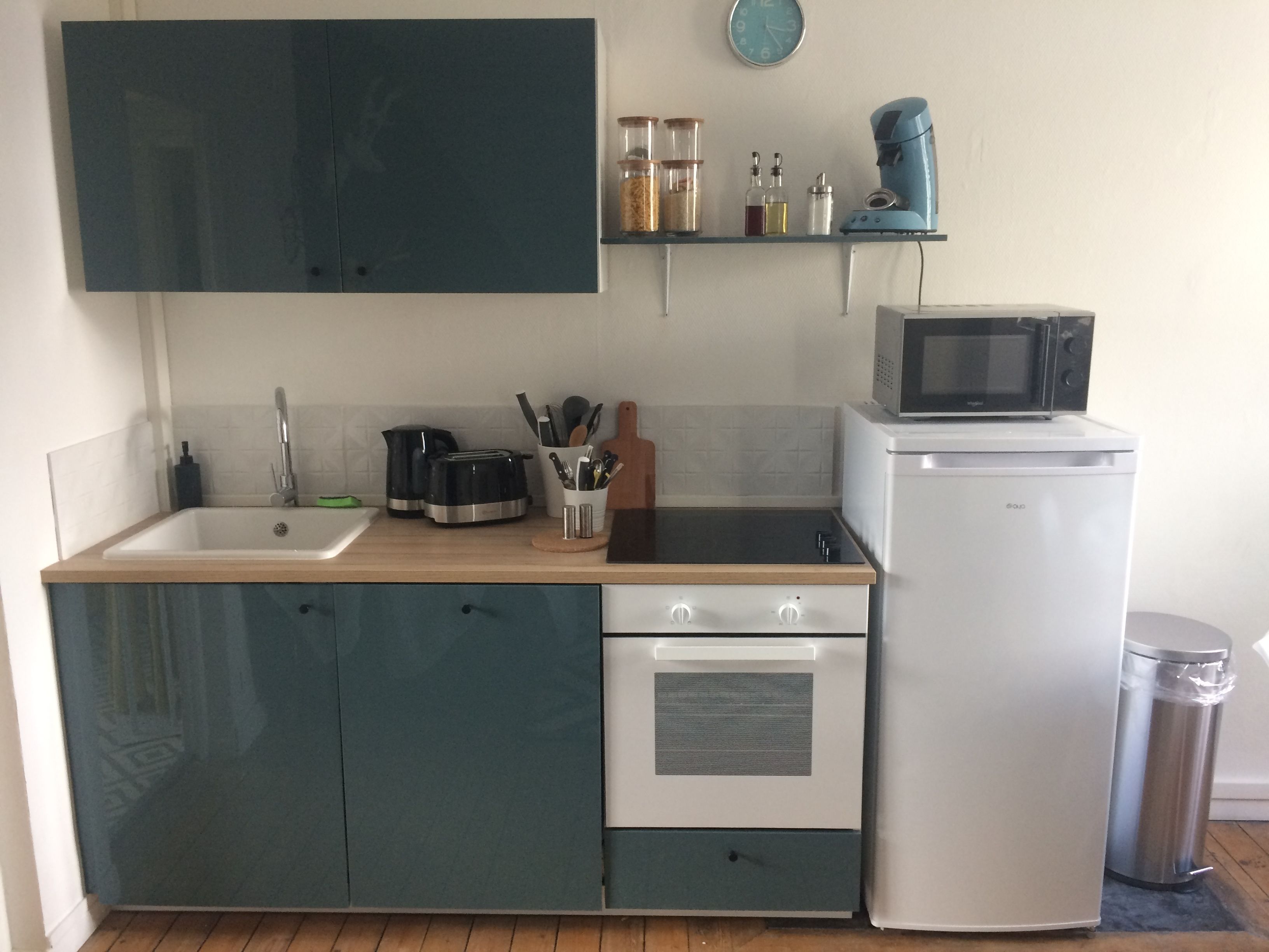 A compact kitchen with a sink, stove, microwave, and a small refrigerator.