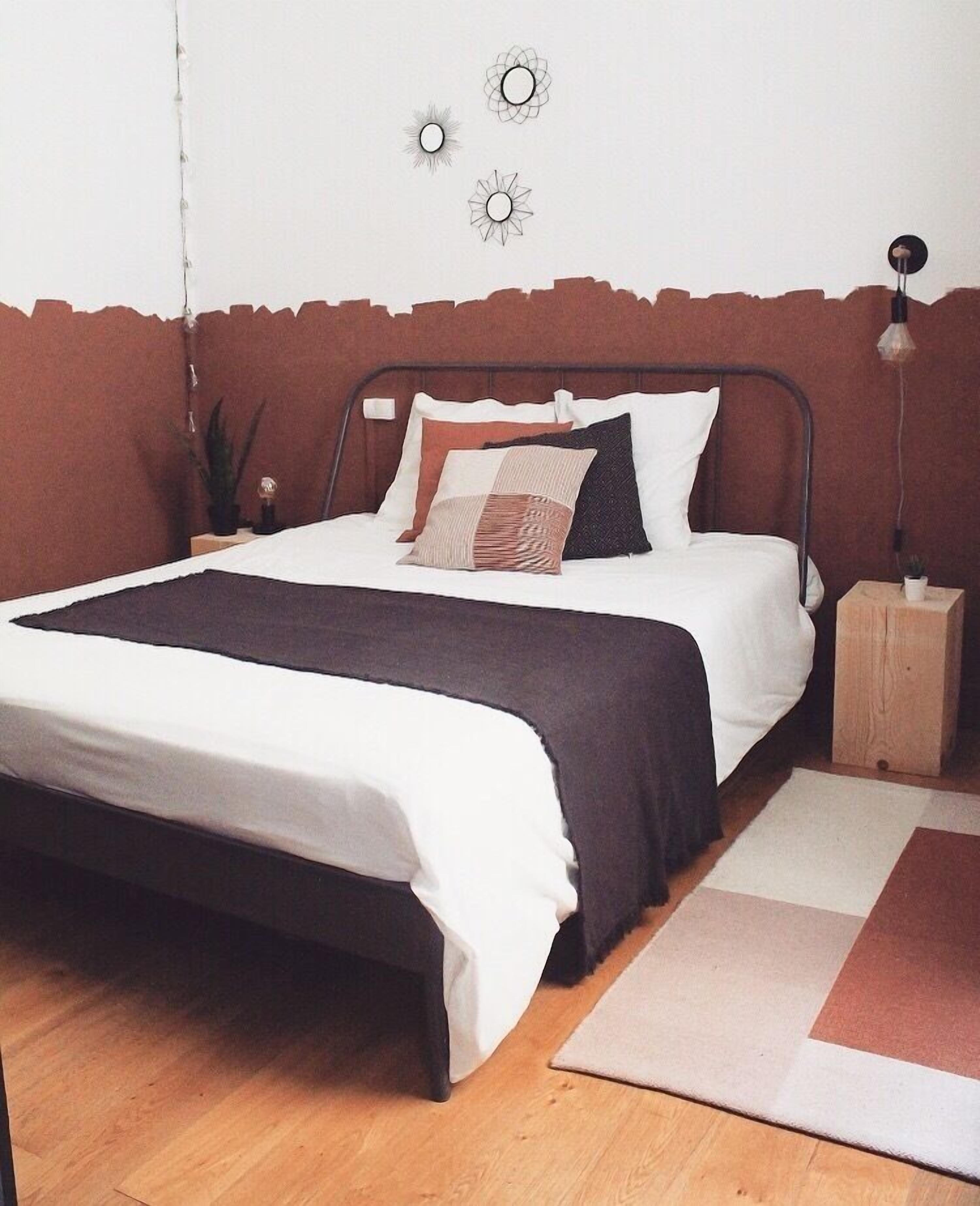 A bedroom with a bed, a nightstand, a wall clock, and a small plant.