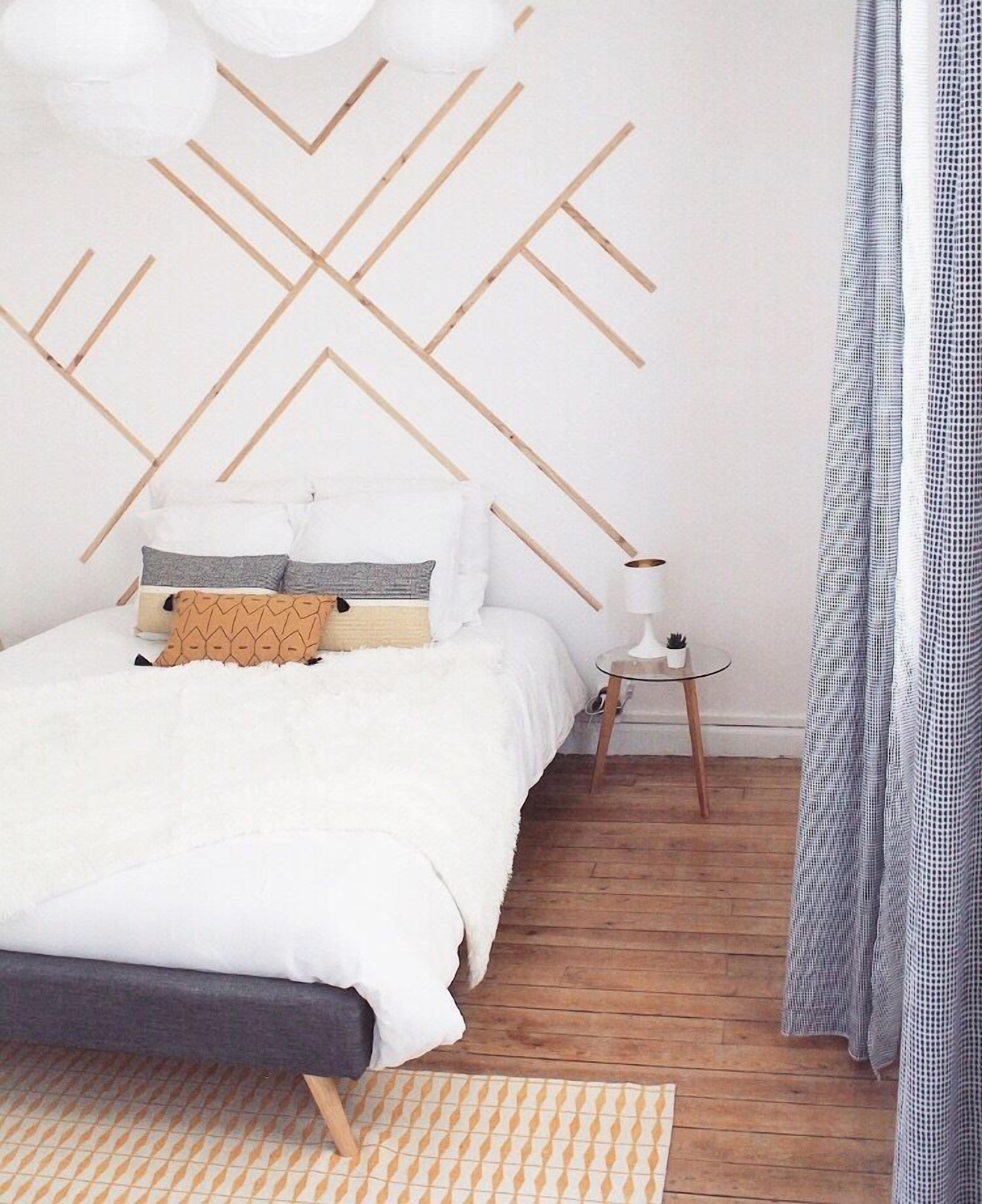 Een slaapkamer met een bed, nachtkastje en een lamp.