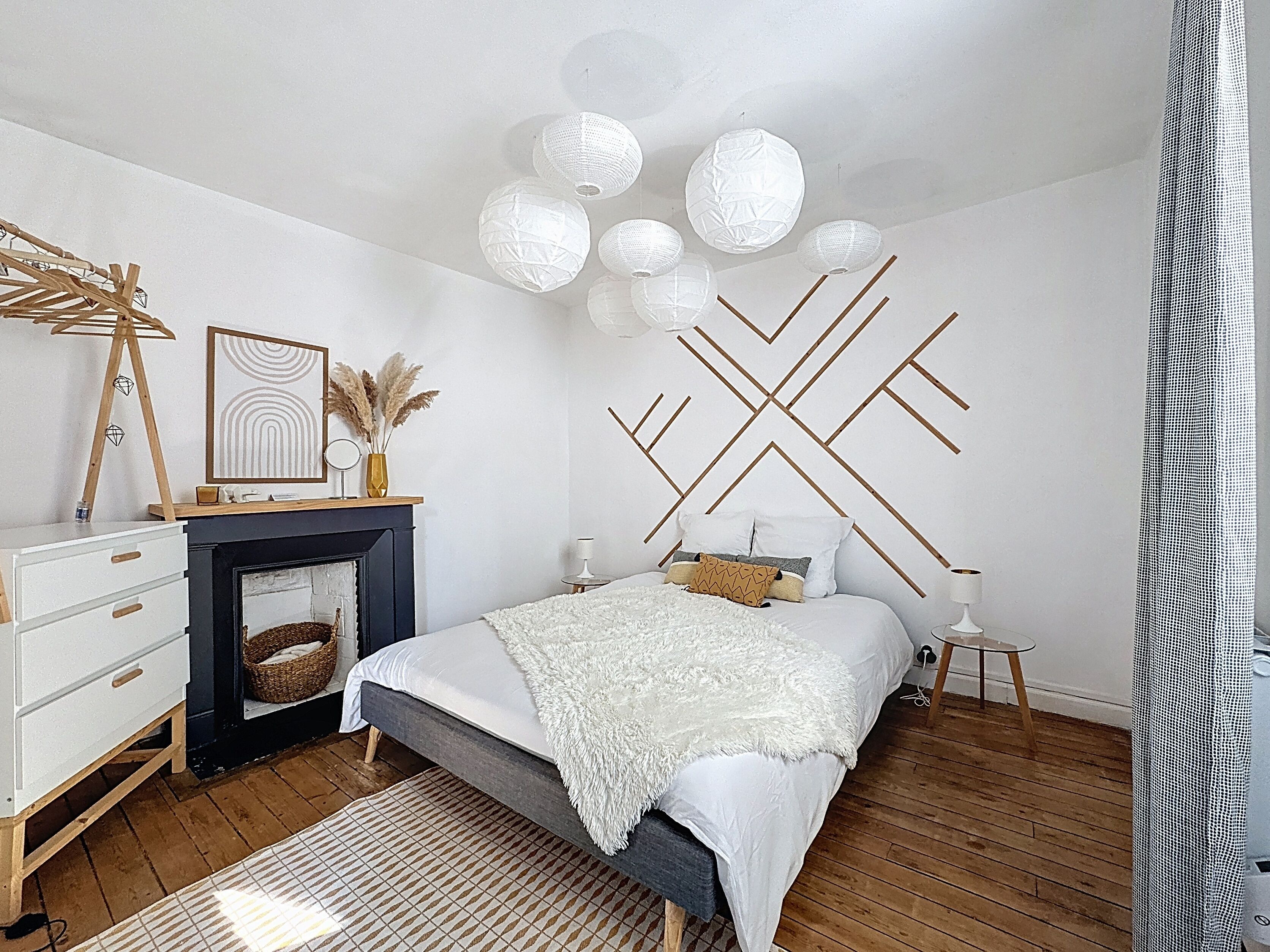 Une chambre à coucher moderne avec un lit, une commode et une cheminée.