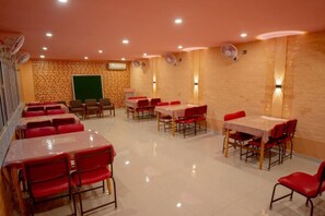 A dining area with tables and chairs, a brick wall, and ceiling fans. - Galaxy Guest House (Siddharthanagar)