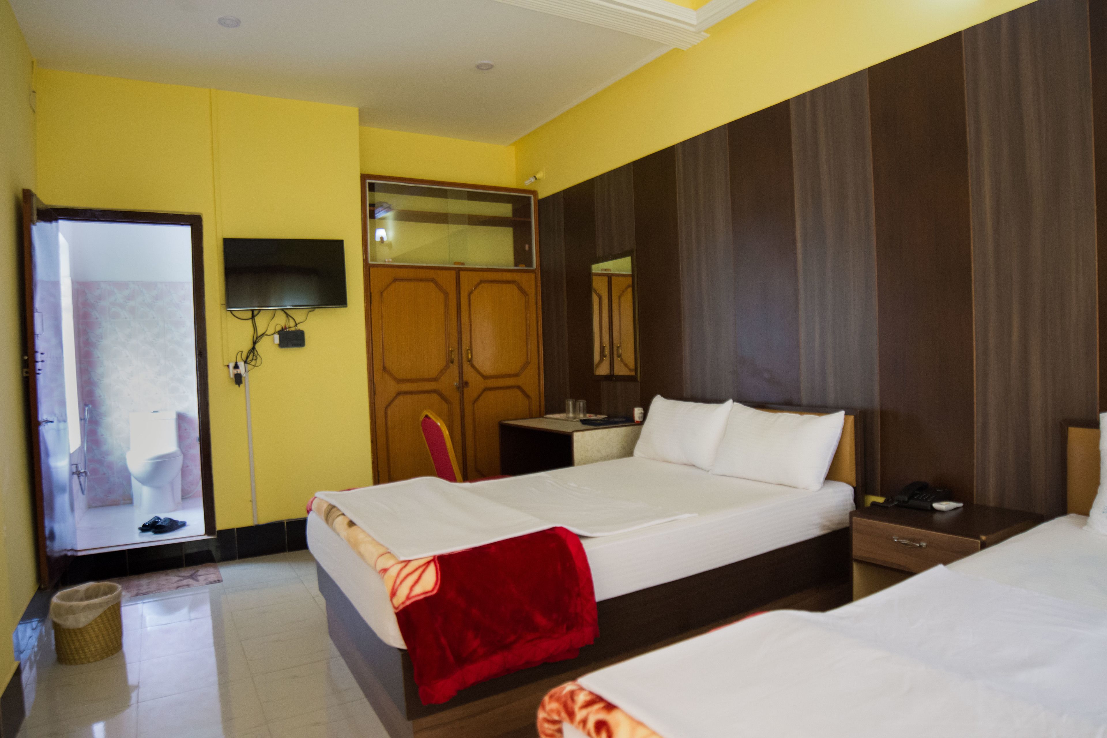 A hotel room with a bed, a bedside table, a TV mounted on the wall, and a mirror.