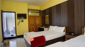 A hotel room with a bed, a bedside table, a TV mounted on the wall, and a mirror.