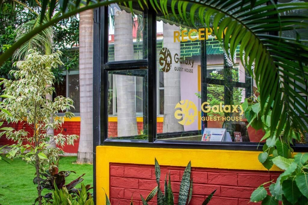 A reception area with a Galaxy Guest House sign, a glass window, and a brick wall.