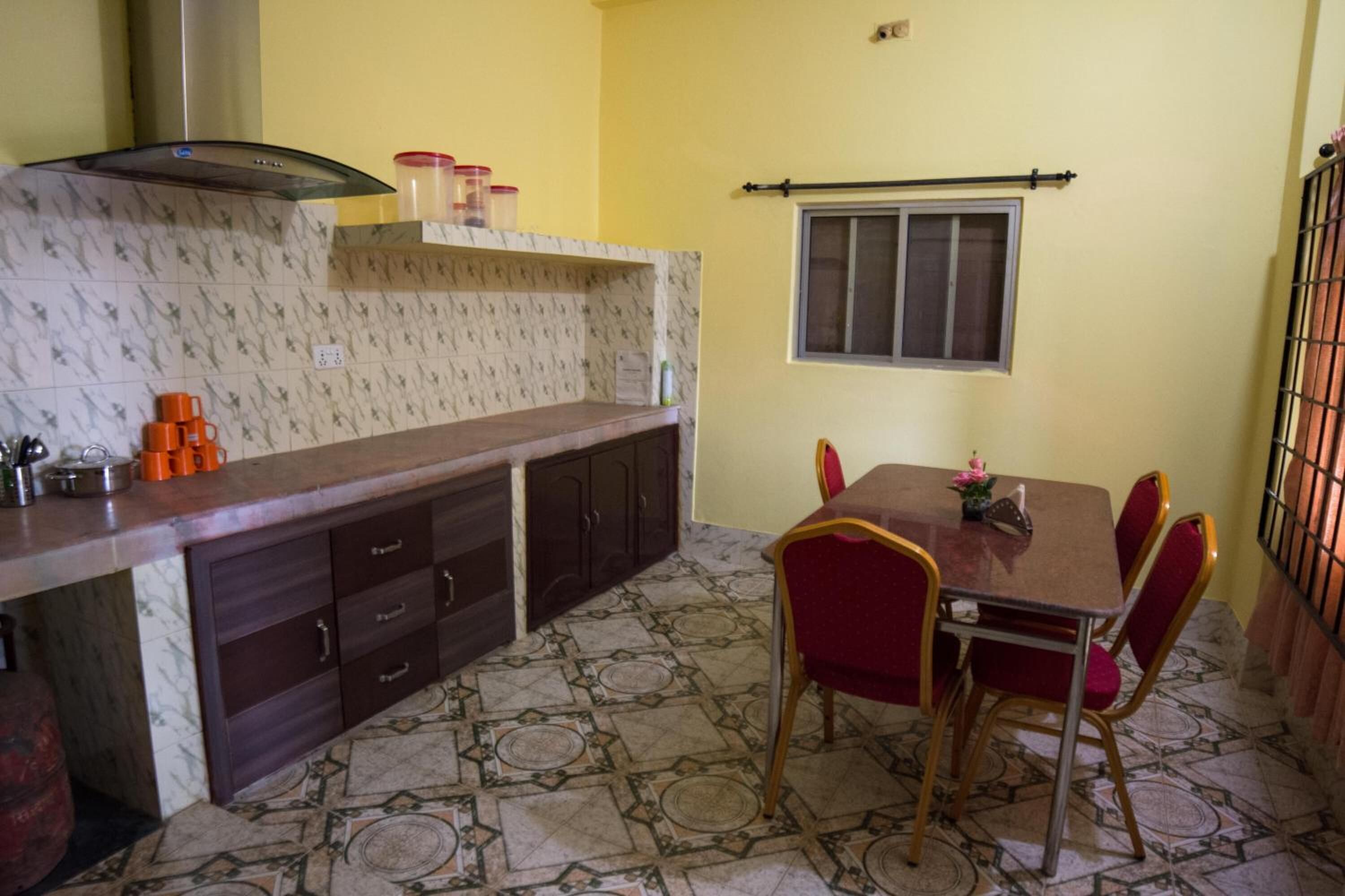 Una cocina con salpicadero de mármol, armarios de madera oscura, una estufa a gas y una zona de comedor con mesa y sillas.
