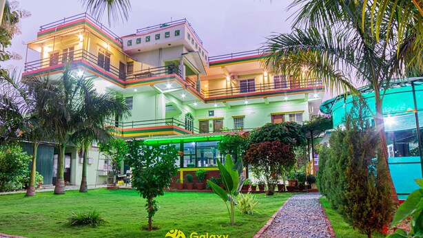 Un hotel de varios pisos con un jardín cuidado y un camino de grava.