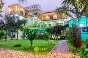 Un hotel de varios pisos con un jardín cuidado y un camino de grava.