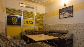 Una habitación con un letrero de Galaxy, sofás estampados, una mesa y un cuadro en la pared.