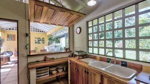 Une cuisine avec des meubles en bois, un évier et une fenêtre donnant sur un paysage verdoyant.