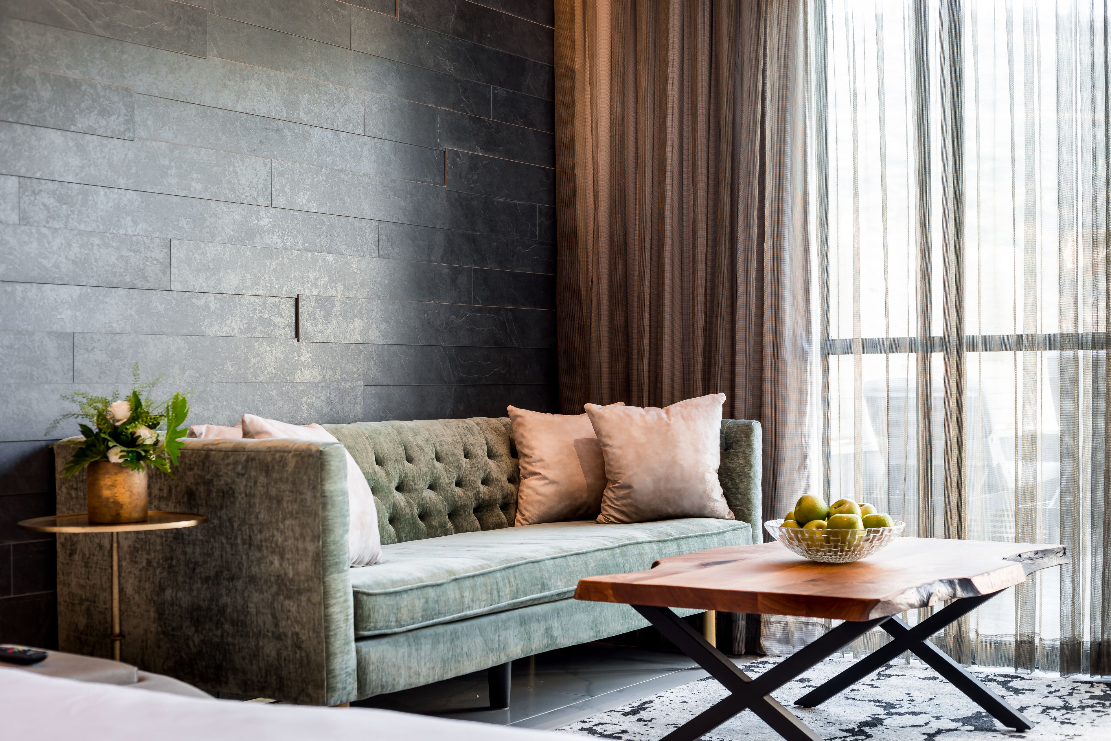A modern living room with a grey sofa, a round wooden coffee table, and a vase with flowers.