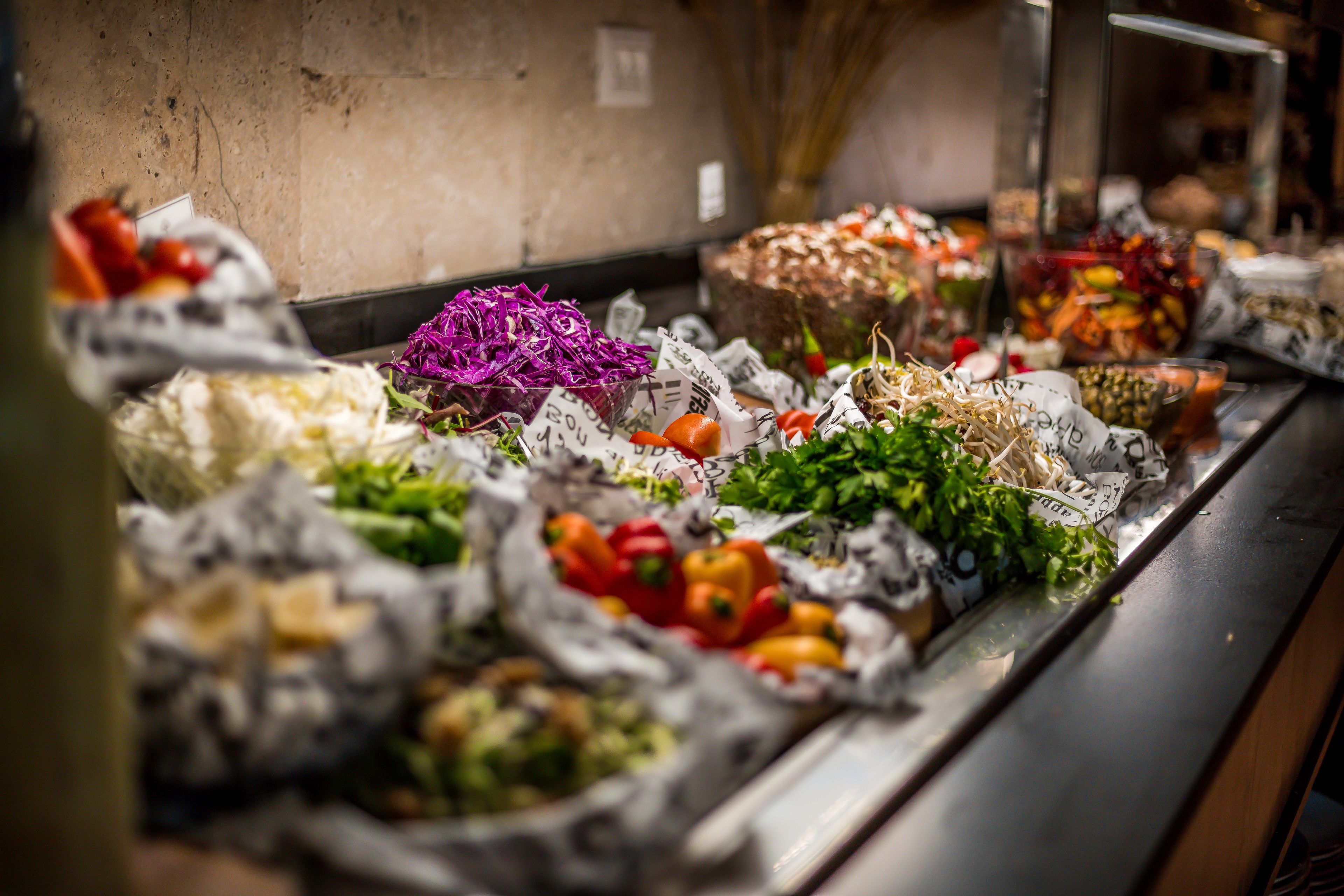 Un bufé con diversas opciones de comida, incluyendo verduras y ensaladas, dispuestas sobre un mostrador.