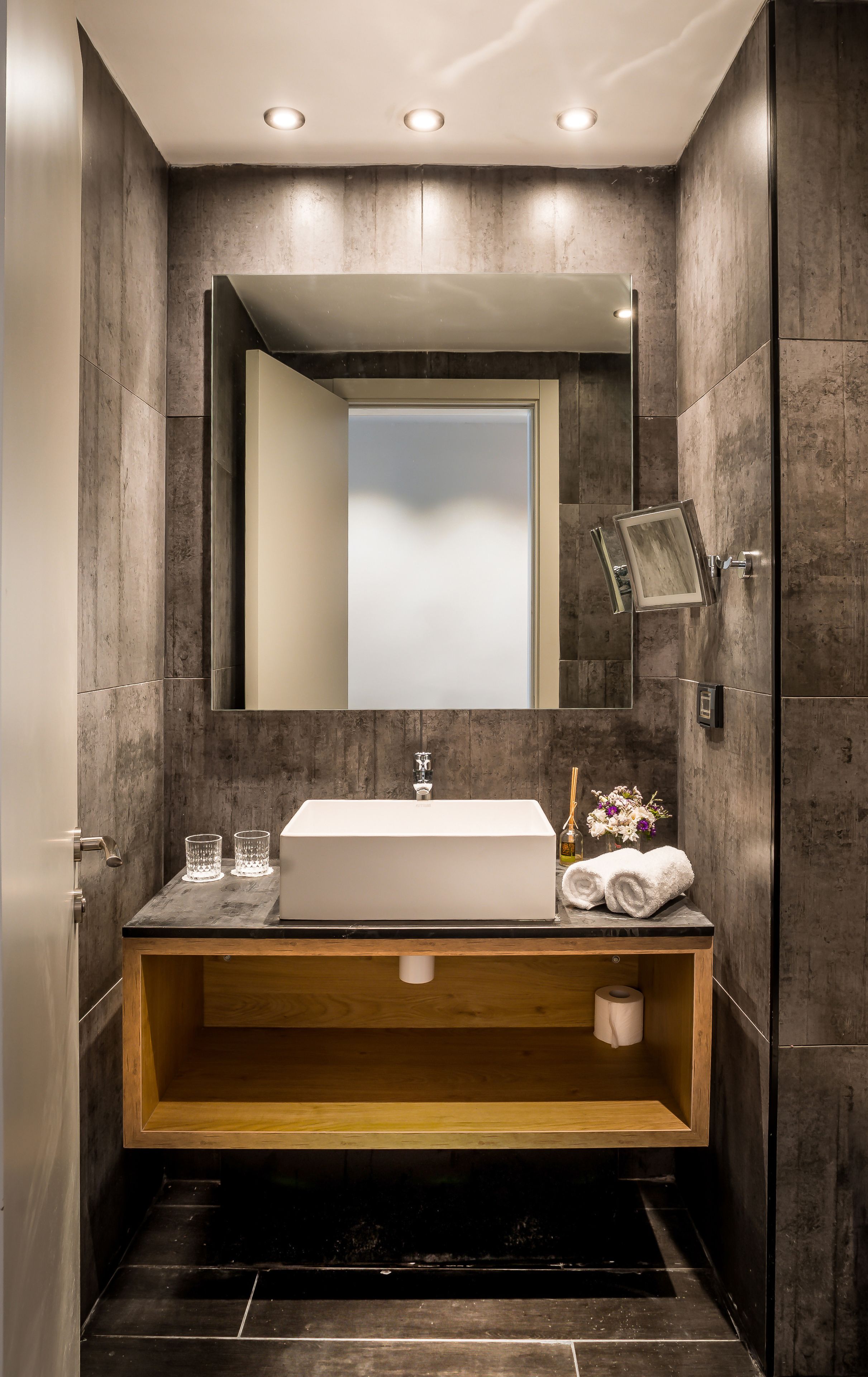 Une salle de bain moderne avec un grand miroir, un lavabo rectangulaire et un meuble-lavabo en bois.