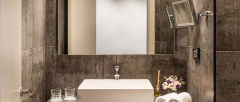 Un baño moderno con un espejo grande, un lavamanos rectangular y un mueble de tocador de madera.