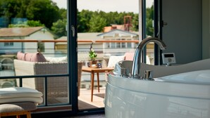 A modern bathroom with a large bathtub, a glass shower enclosure, and a view of the outdoor balcony area.