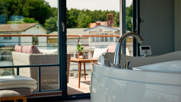 A modern bathroom with a large bathtub, a glass shower enclosure, and a view of the outdoor balcony area. - VILLA EMMA 4A- luxury with sauna, whirlpool, fireplace, view, for 8 pers.+ Babybet (Sellin)
