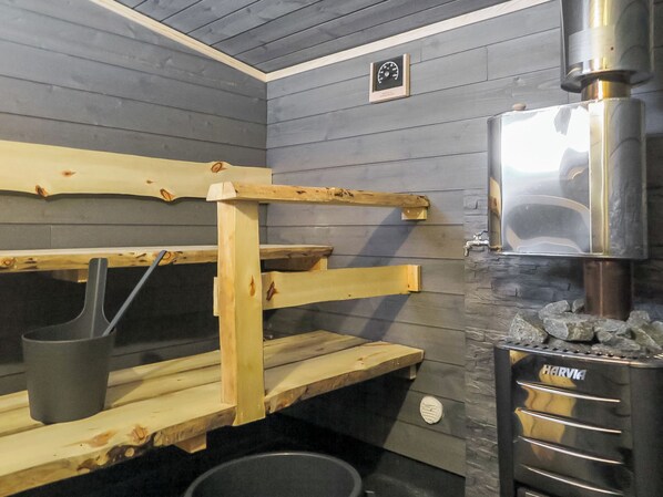 Uma sala de sauna com bancos de madeira e uma parede de pedra.