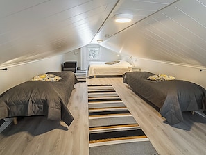 A compact, attic-style bedroom with two beds, a small desk, and a framed picture on the wall. - Pallaskieppi by Interhome (Raattama)