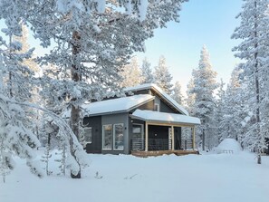Uma cabana rodeada por árvores cobertas de neve.