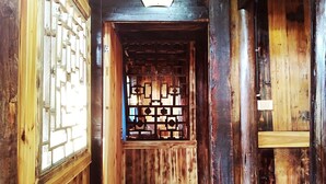 Interior de madera con una puerta de celosía tradicional y un estante pequeño.