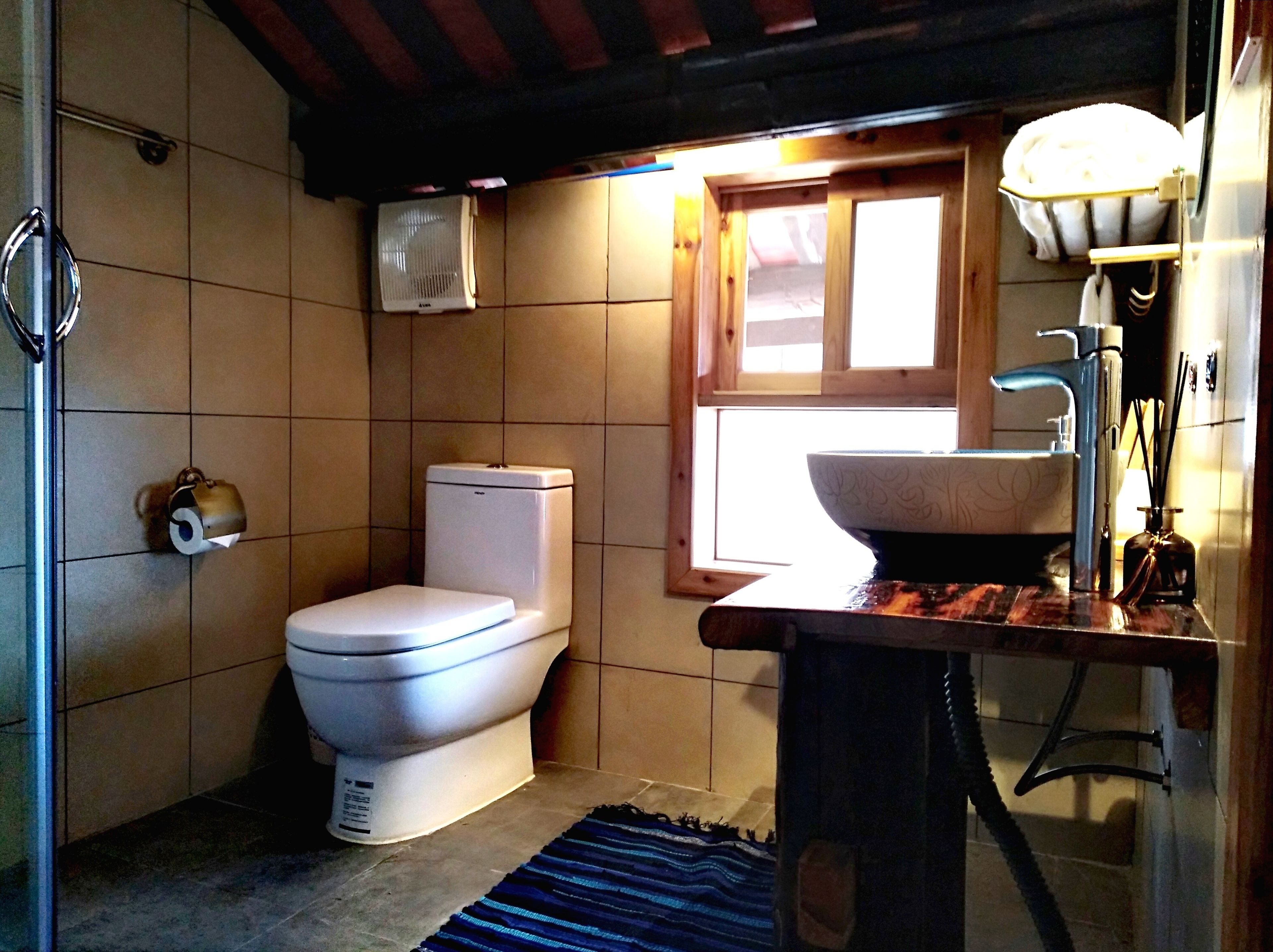 Een compacte badkamer met toilet, wastafel en raam.