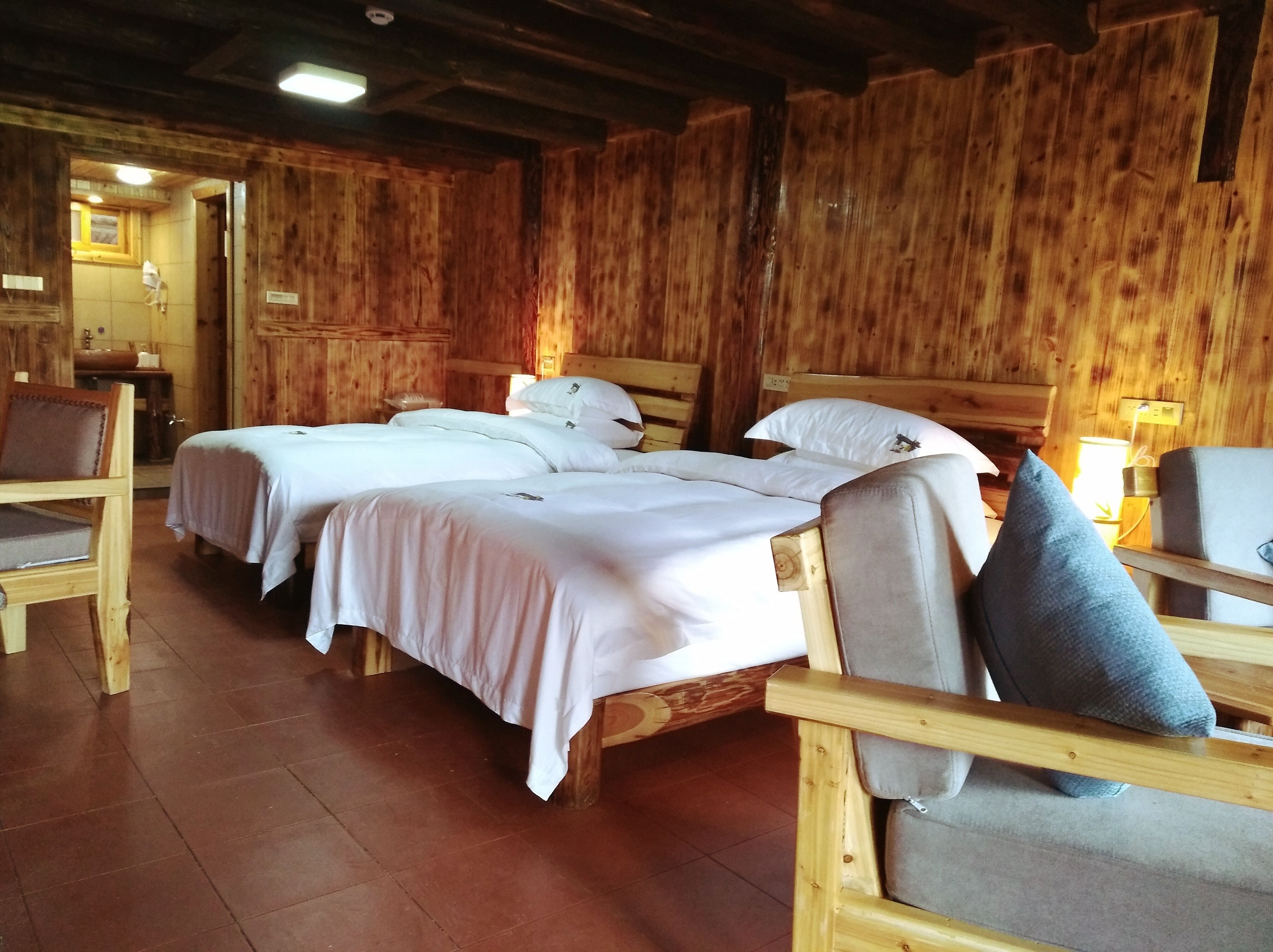 A wooden cabin-style room with three beds, wooden furniture, and a rustic ambiance.