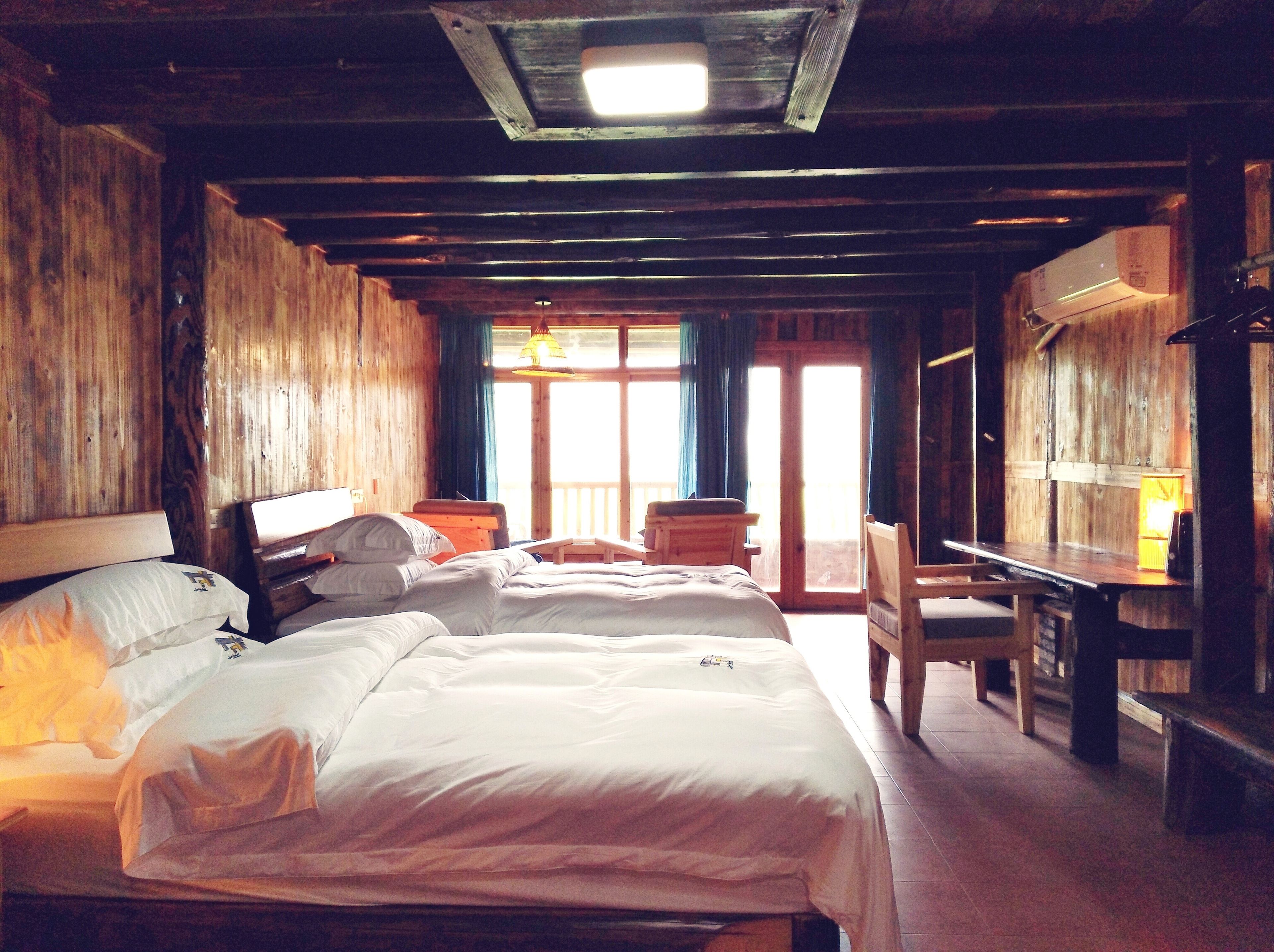A wooden room with two beds, a desk, and a chair.