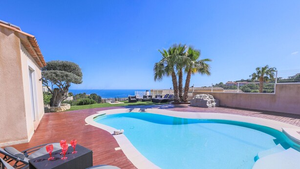 A swimming pool with a wooden deck, lounge chairs, and a table with red glasses. - LA CORNICHE D'ARGENT VI4136 by RIVIERA HOLIDAY HOM (Niza)