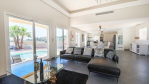 A spacious living room with a black leather sofa, a glass coffee table, and a view of a swimming pool. - LA CORNICHE D'ARGENT VI4136 by RIVIERA HOLIDAY HOM (Niza)