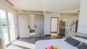A modern hotel room with a large bed, a sliding door leading to a balcony, a bathroom with a mirror and wooden decor, and a view of the outdoors. - LA CORNICHE D'ARGENT VI4136 by RIVIERA HOLIDAY HOM (Niza)