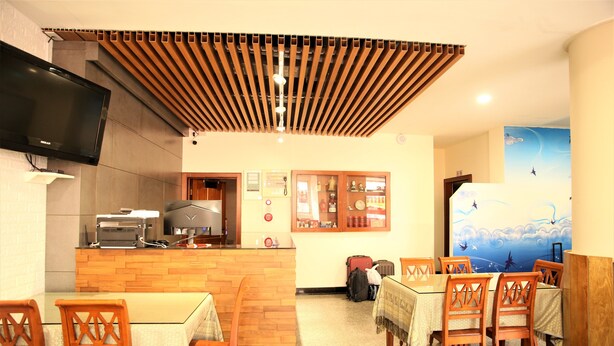 Un restaurante con mobiliario de madera, una barra con una parrilla y un televisor en la pared.