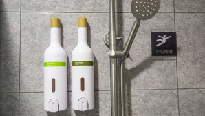 Zona de ducha con cabezal de ducha manual y dos botellas de champú y gel de baño.