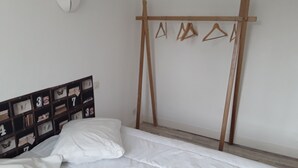 Un dormitorio con una cama, un perchero de madera y una estantería empotrada con compartimentos numerados.