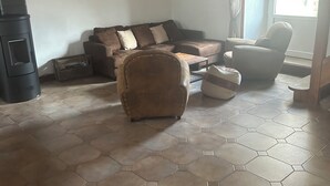 Una sala de estar con un sofá de cuero marrón, una mesa de centro de madera y un piso con baldosas hexagonales.