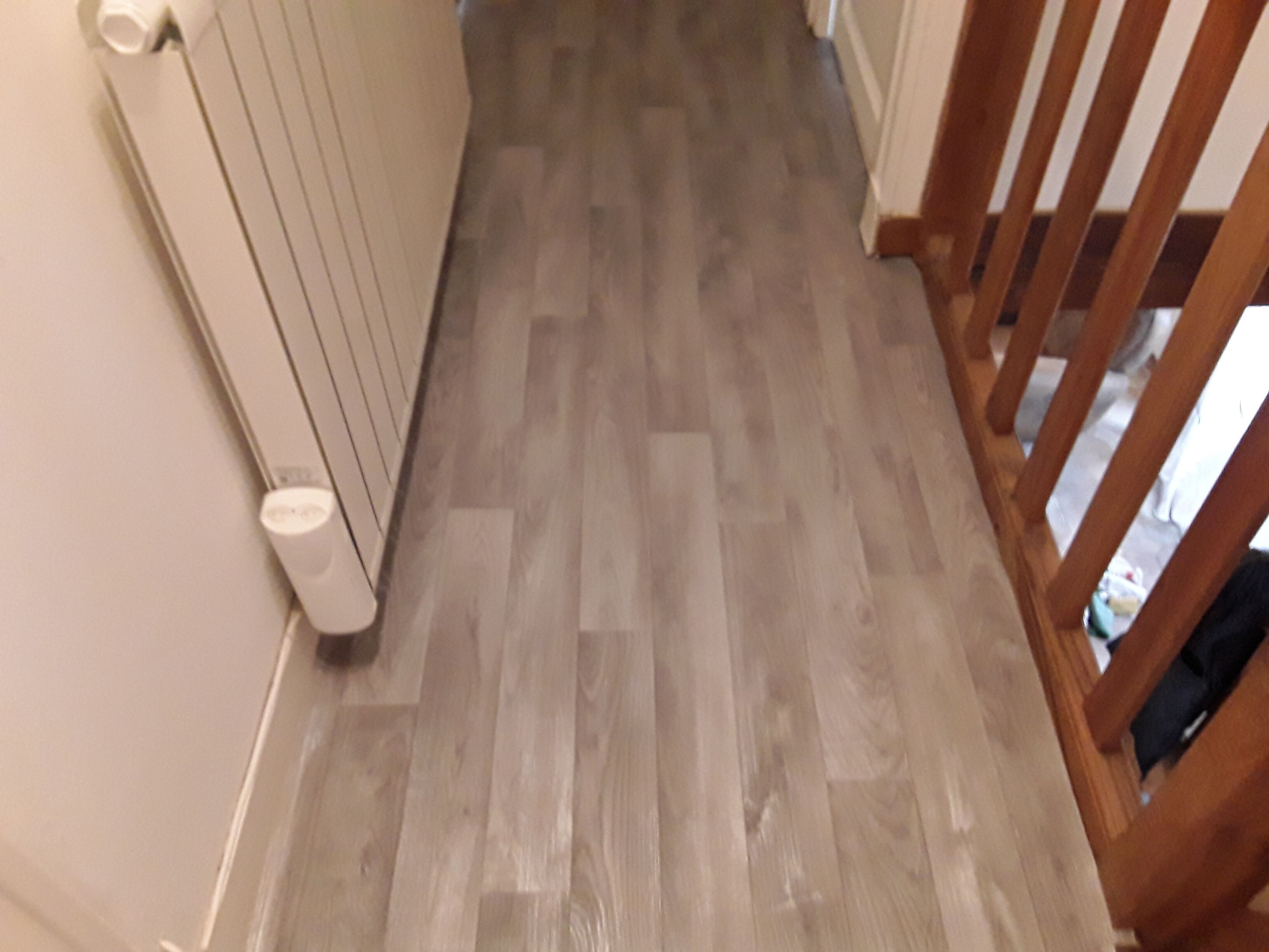 A wooden floor with a radiator and a white wall.