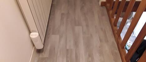 A wooden floor with a radiator and a white wall.