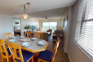 A dining area with a table set for four, a sofa, and a TV in the background.