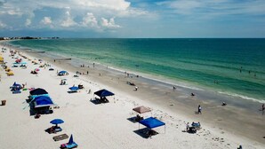 Une plage avec de nombreux parasols et des chaises longues, un rivage sablonneux et l’océan.