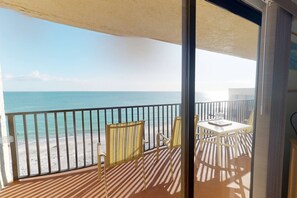 A balcony with a view of the beach and ocean.