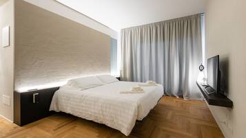 Una camera da letto moderna con un letto, una televisione e una finestra con tende.