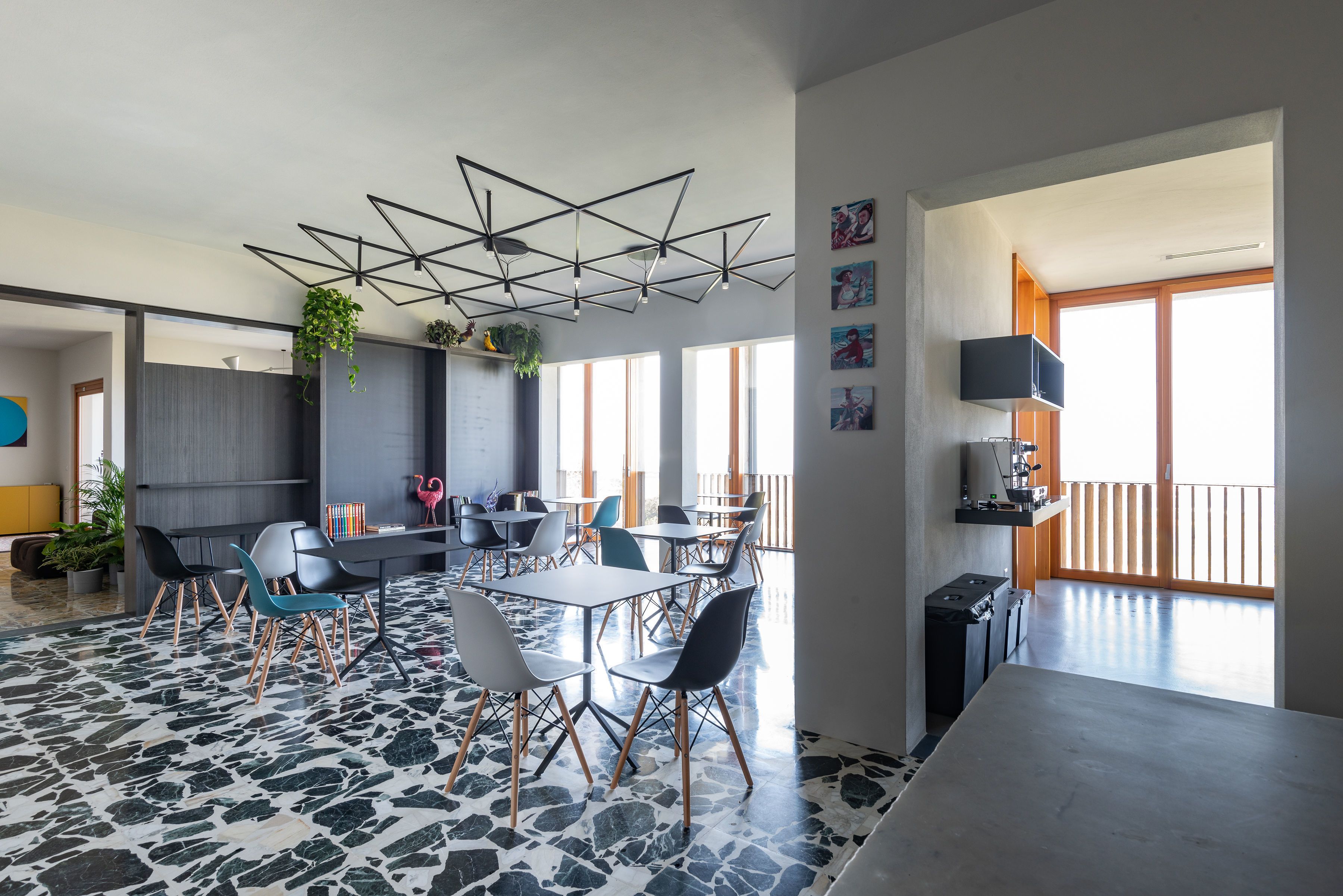 Un'area pranzo moderna con un design geometrico del soffitto, diverse opzioni di seduta e vista sull'esterno.