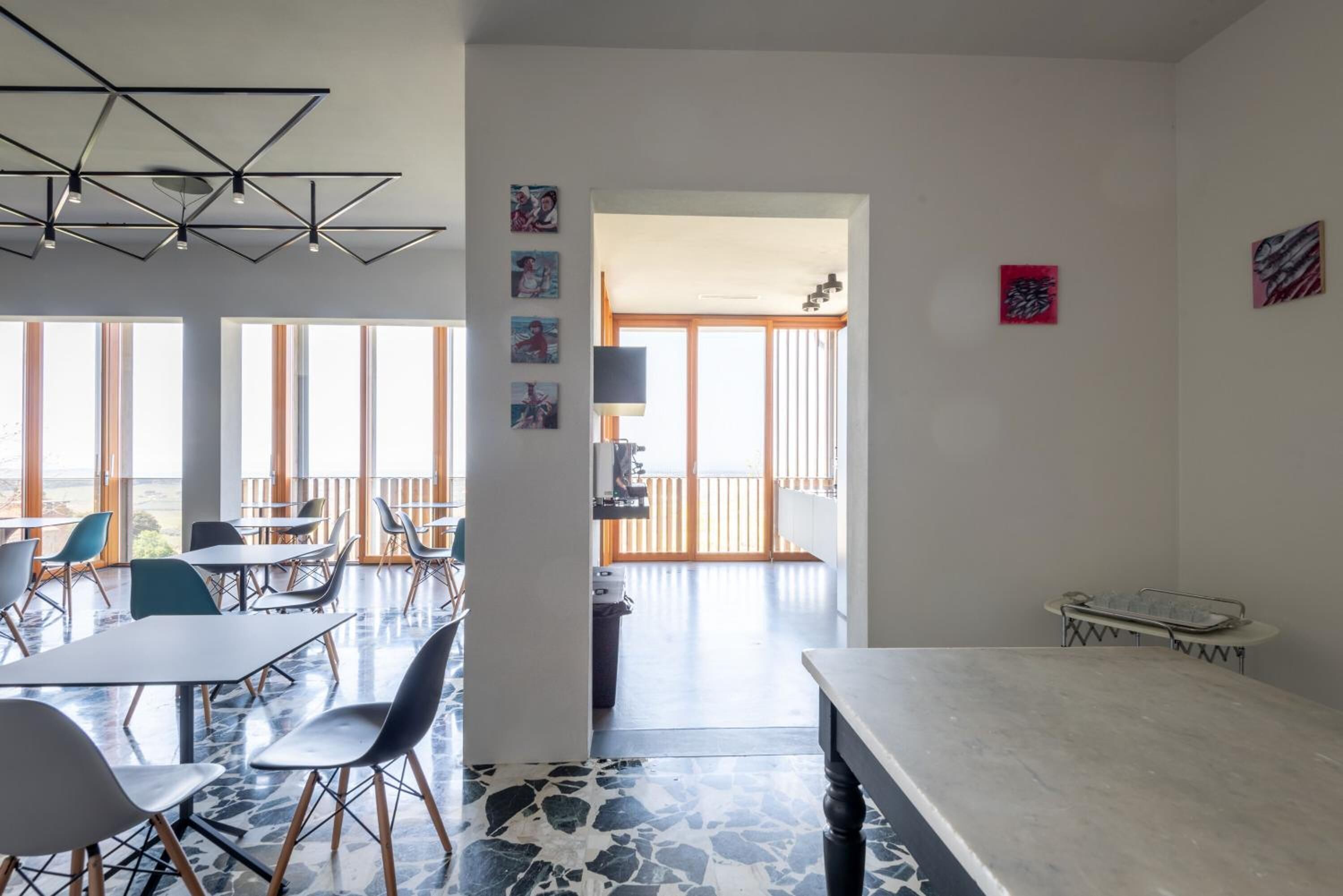 Un espace repas moderne, doté de tables et de chaises, de grandes fenêtres et offrant une vue sur l’extérieur.