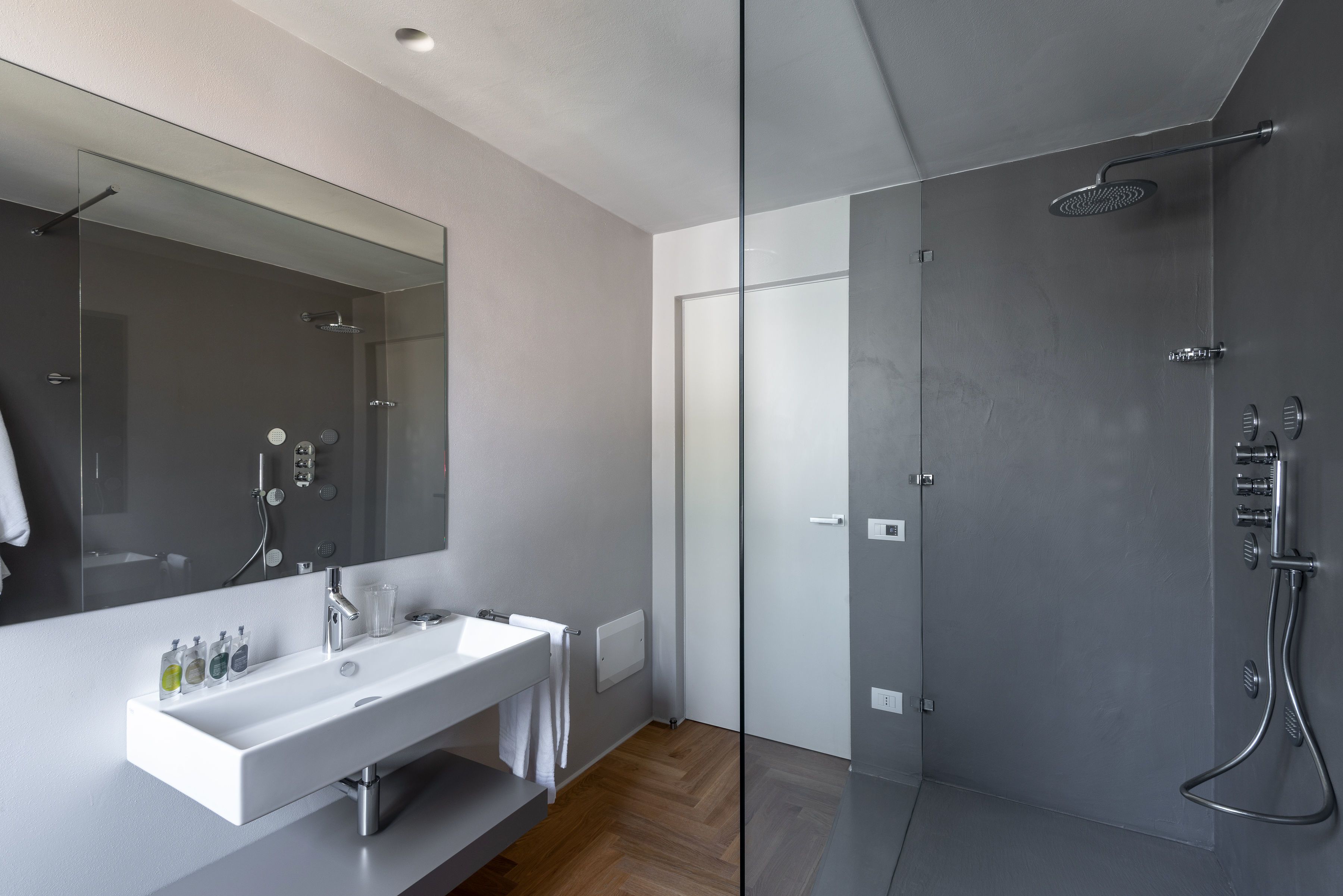 A modern bathroom with a glass shower enclosure, a large mirror, and a white vanity with a sink.