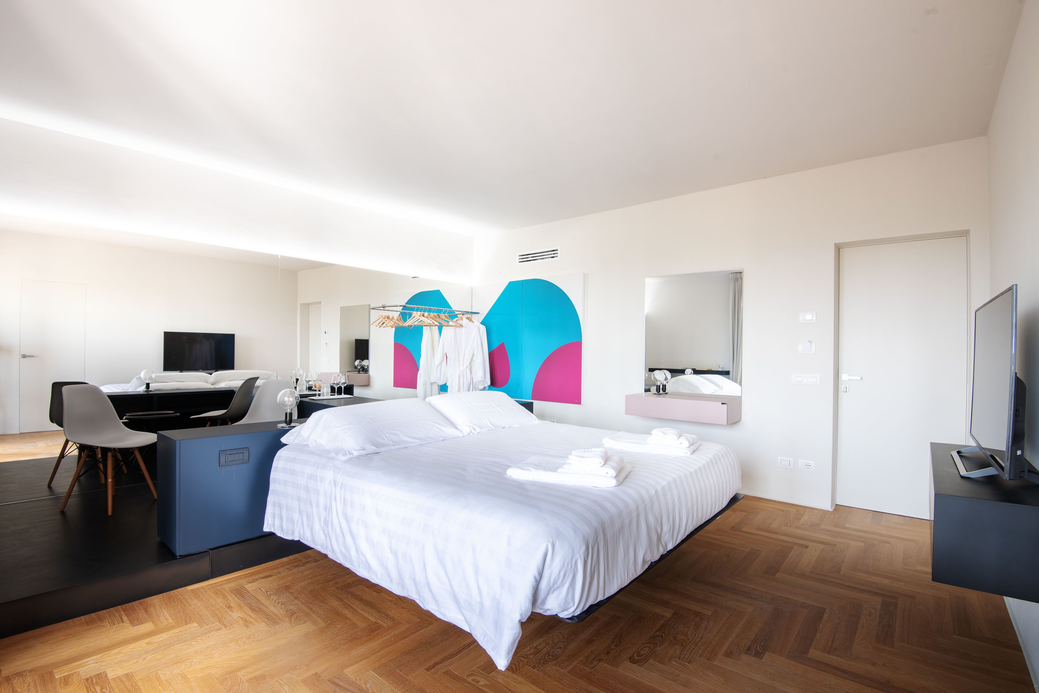 Una habitación de hotel moderna con una cama grande, un escritorio, una silla, un televisor y un baño con espejo.