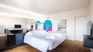 Una habitación de hotel moderna con una cama grande, un escritorio, una silla, un televisor y un baño con espejo.