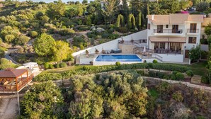 A large house with a swimming pool, surrounded by lush greenery and hills. - Villa HERMIONA - Wake Up To A Golf View (Paphos)