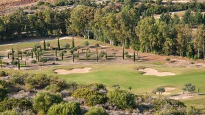 A golf course with sand bunkers, trees, and a hilly landscape. - Villa HERMIONA - Wake Up To A Golf View (Paphos)