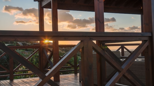 A wooden deck with a view of the sunset and clouds. - Villa HERMIONA - Wake Up To A Golf View (Paphos)