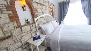 Ein Schlafzimmer mit Ziegelwand, einem weißen Bett und einem Nachttisch mit Lampe.