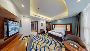 Une chambre d’hôtel avec un grand lit, un canapé, une télévision et un bureau.